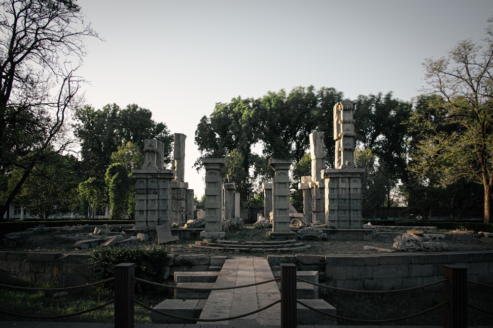 an old cemetery with stone pillars and trees in the background