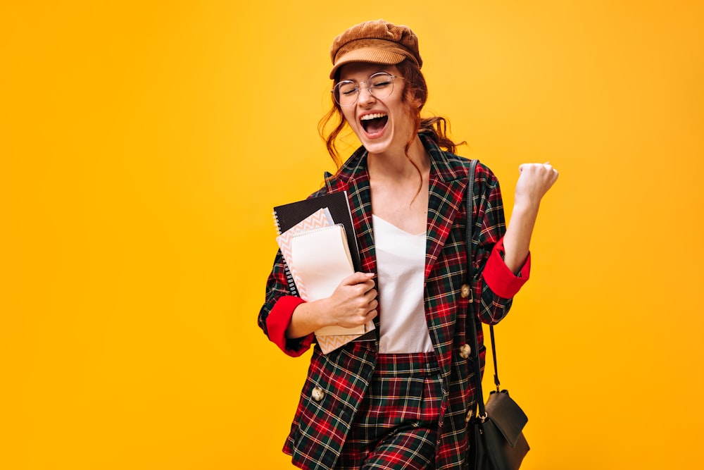 a woman in a plaid jacket holding a book and a bag
