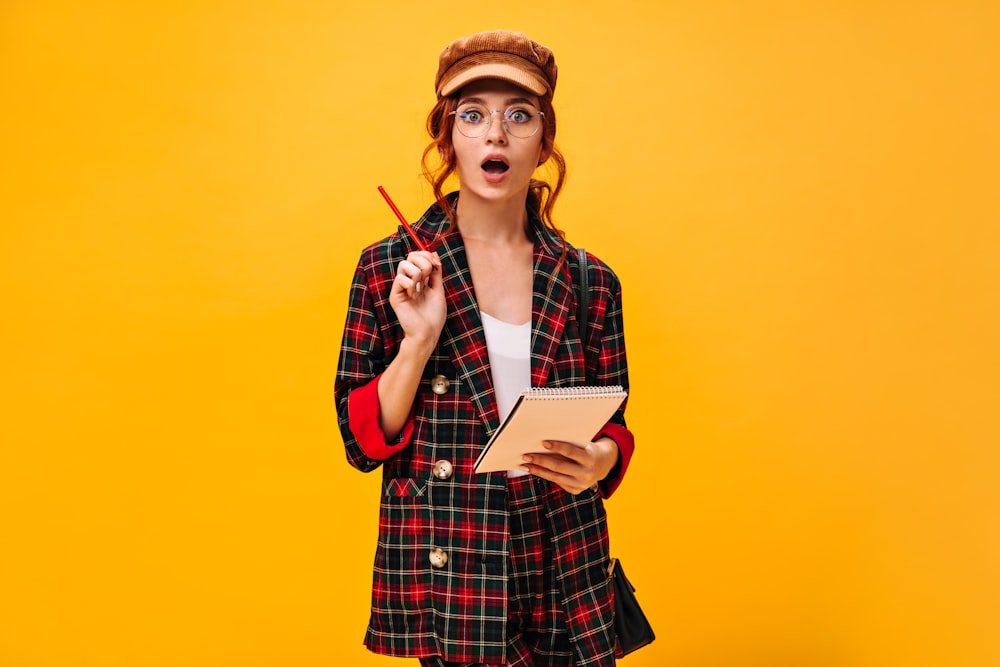 a woman in a plaid jacket holding a pen and notebook