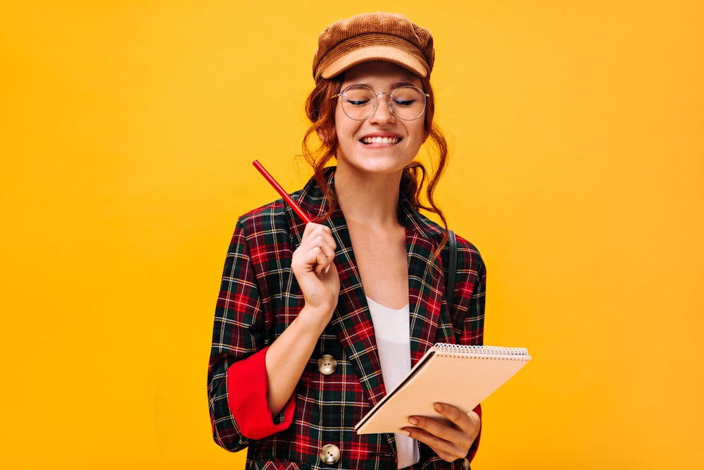a woman in a plaid jacket holding a pen and notebook