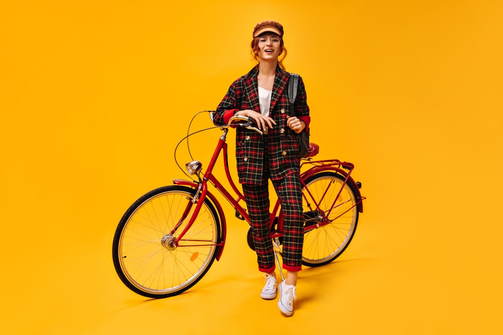 a woman standing next to a bike on a yellow background