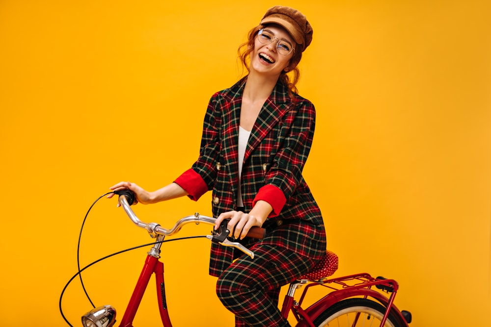 a woman in a red and black checkered suit riding a red bicycle