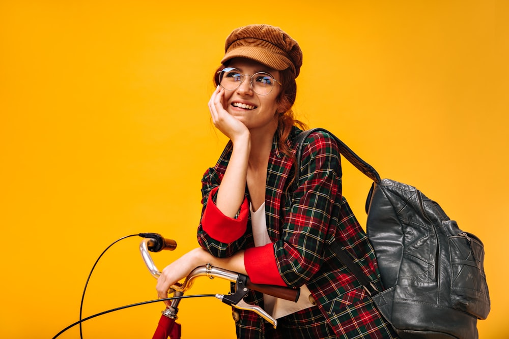 a woman sitting on top of a bike next to a black bag