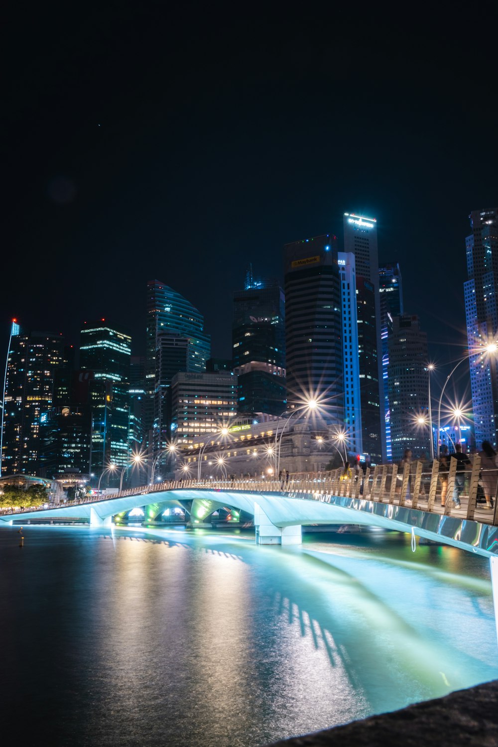 a night scene of a city with a bridge over a body of water