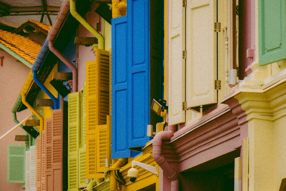 a row of multicolored windows and shutters on a building