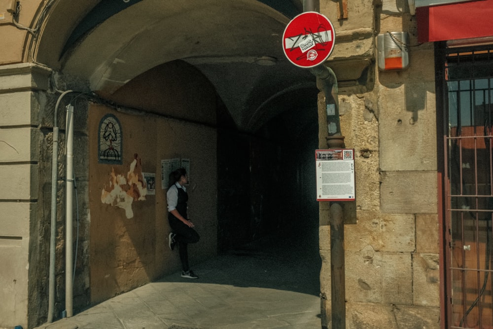 a man walking down a street next to a red and white sign