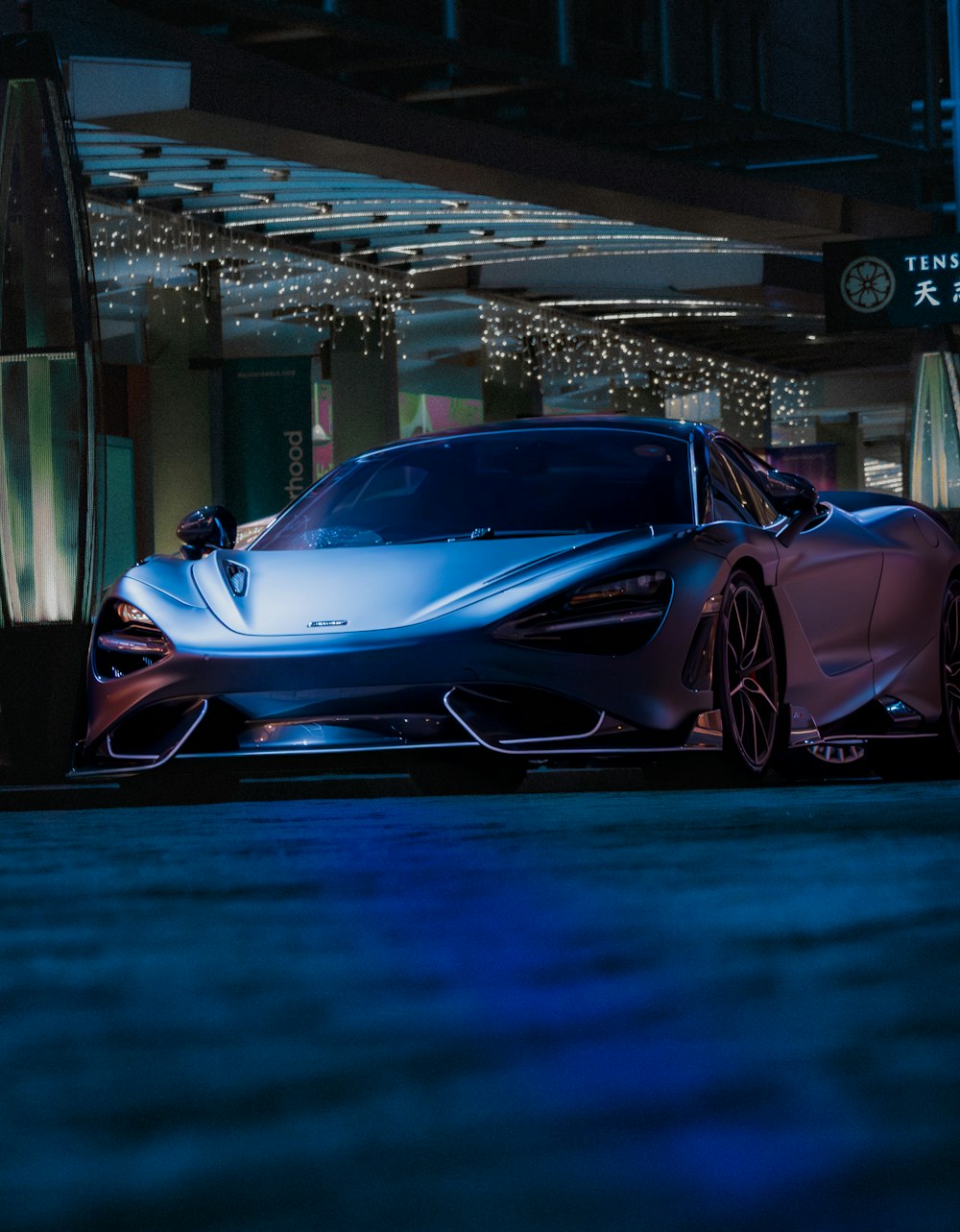 a blue sports car parked in front of a building