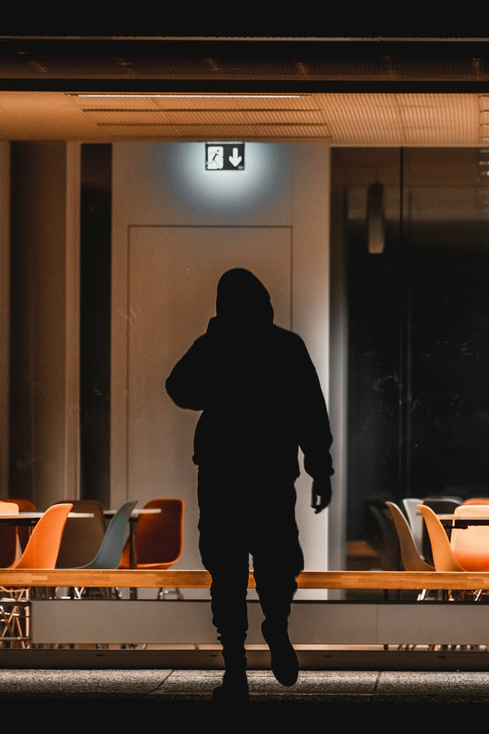 a person in a black hoodie walking past a building