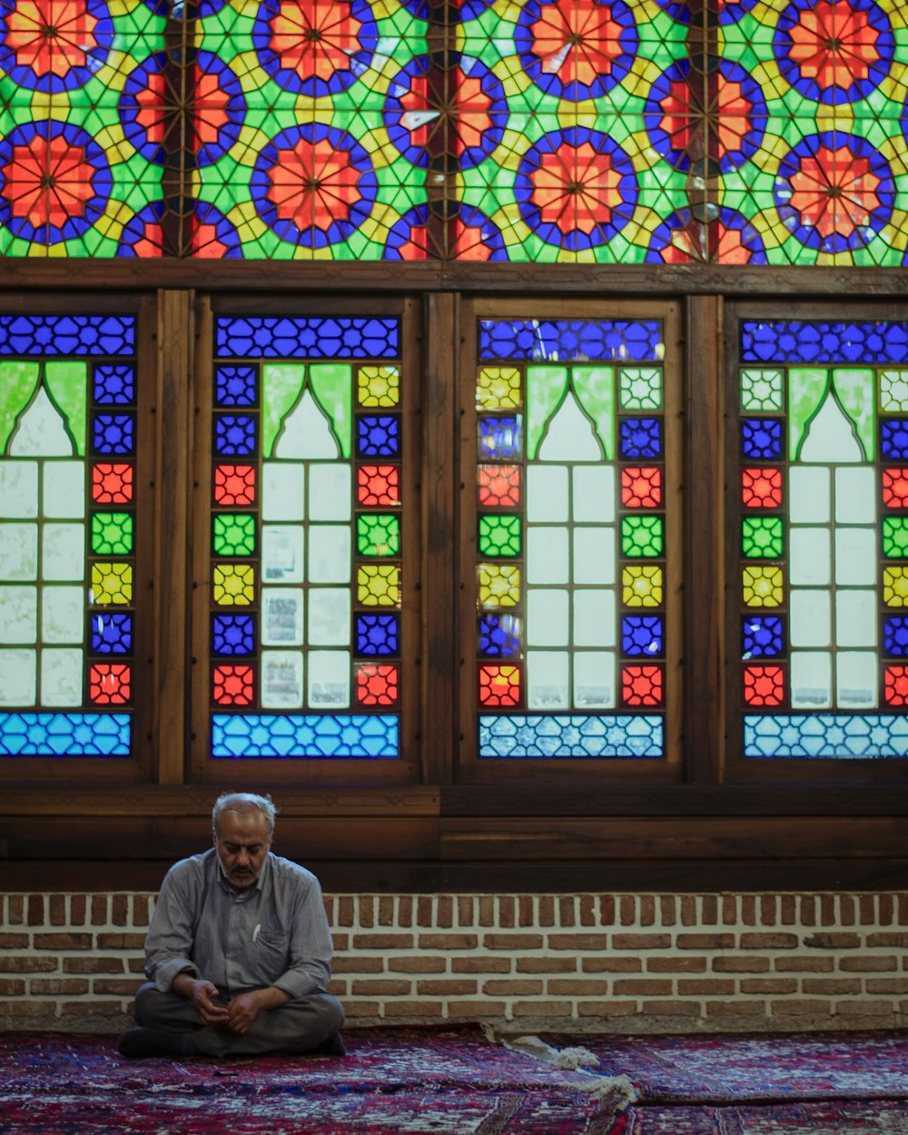 a man sitting on a rug in front of a stained glass window