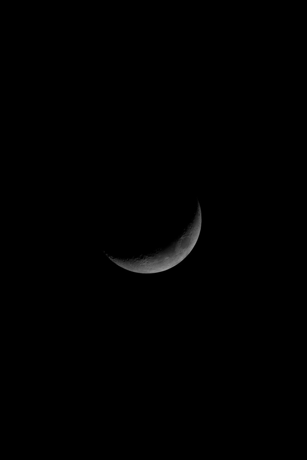 a crescent moon is seen in the dark sky