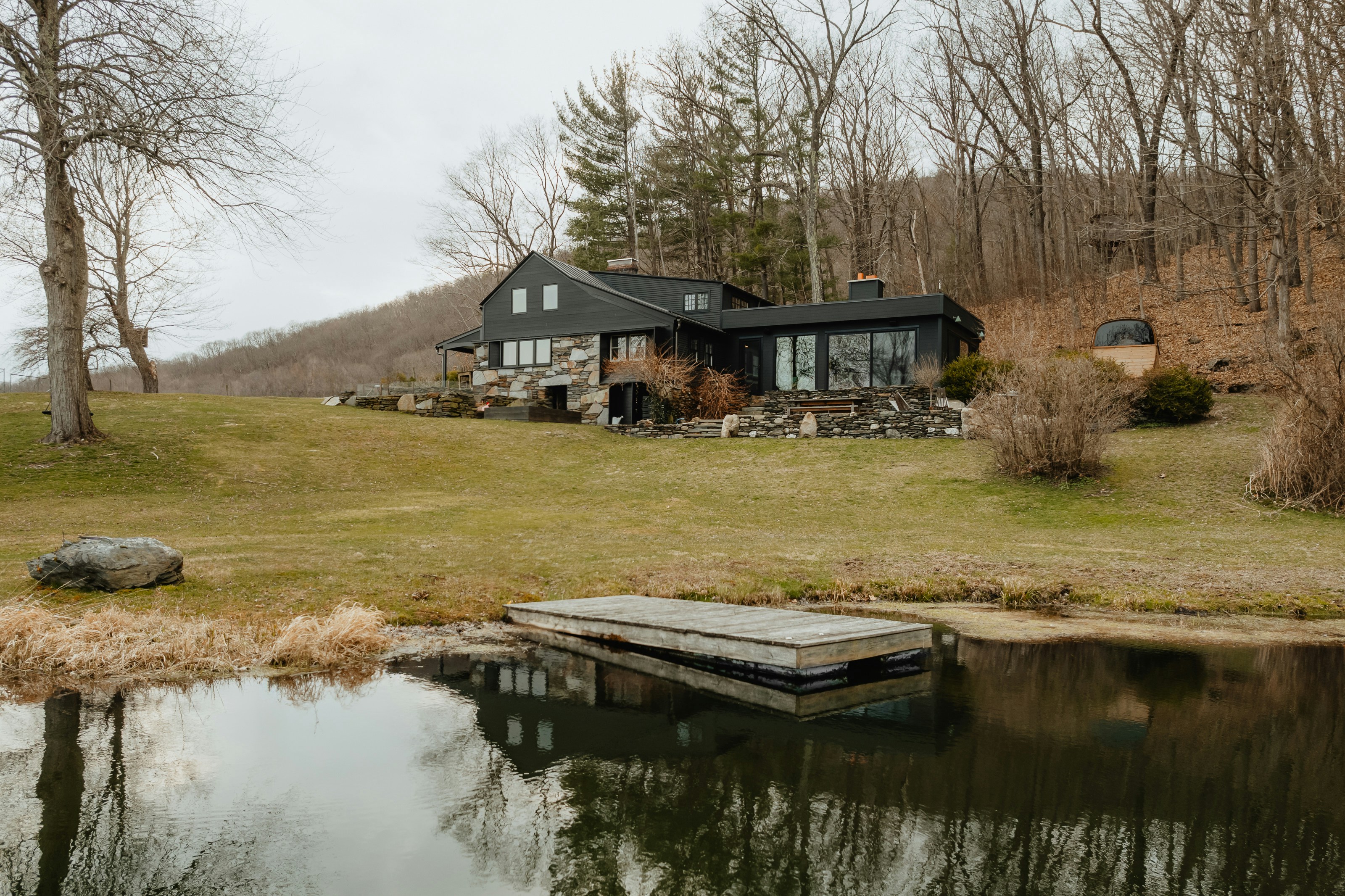 a house sitting on top of a lush green hillside next to a lake