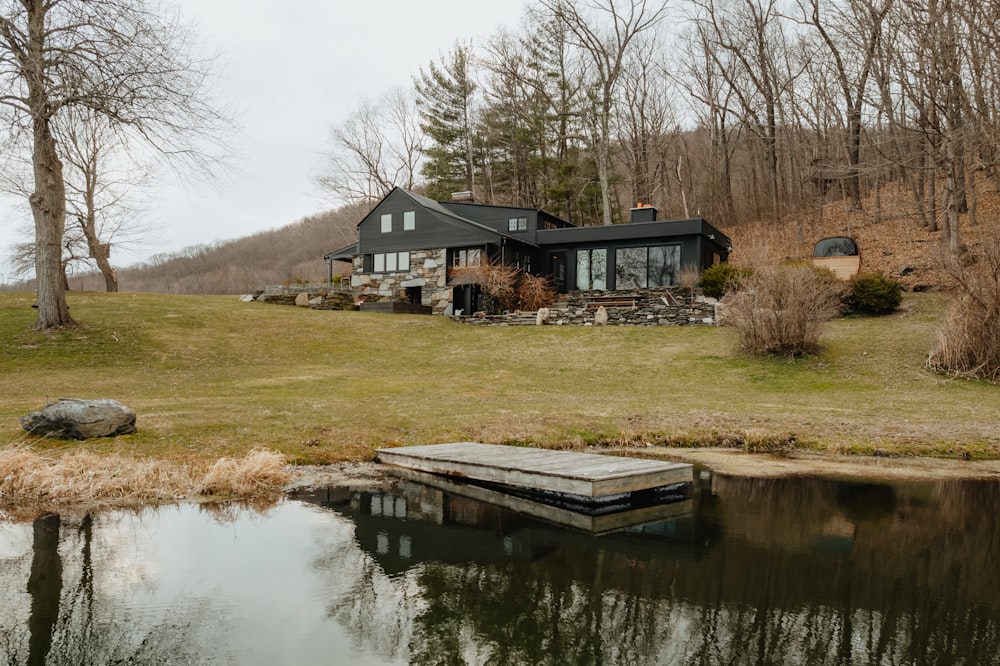 a house sitting on top of a lush green hillside next to a lake