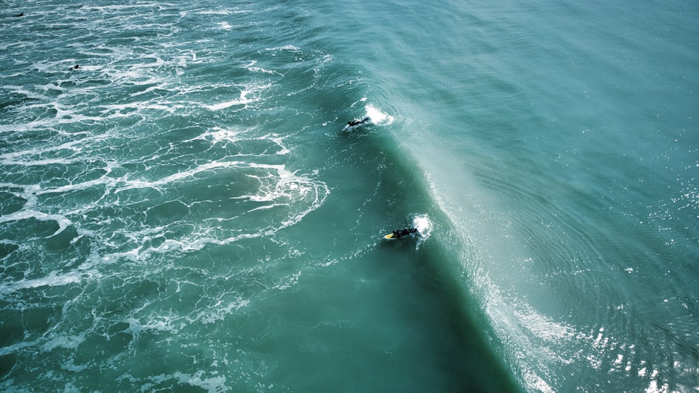 a couple of people riding on top of a wave in the ocean