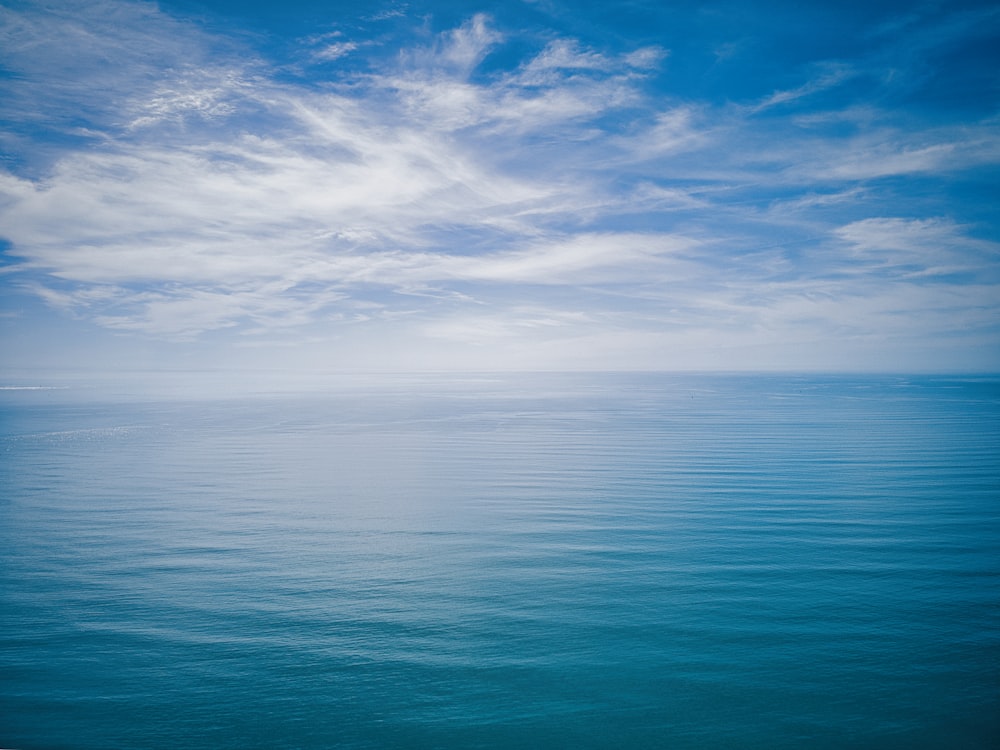 a large body of water sitting under a cloudy blue sky