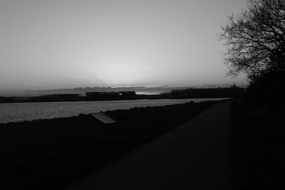 a black and white photo of the sun setting over a body of water