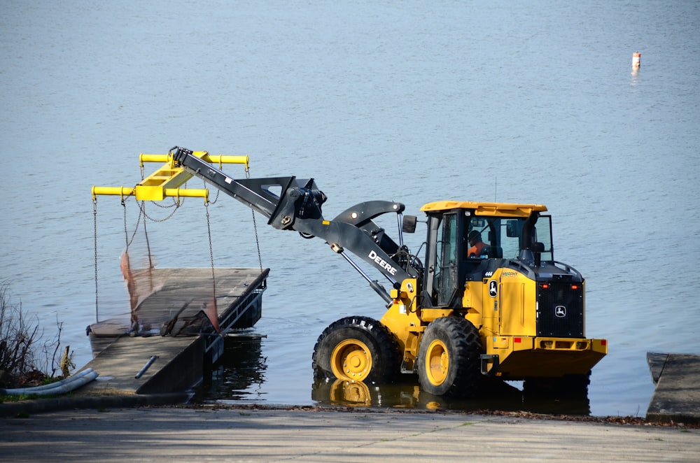 a yellow tractor parked next to a dock