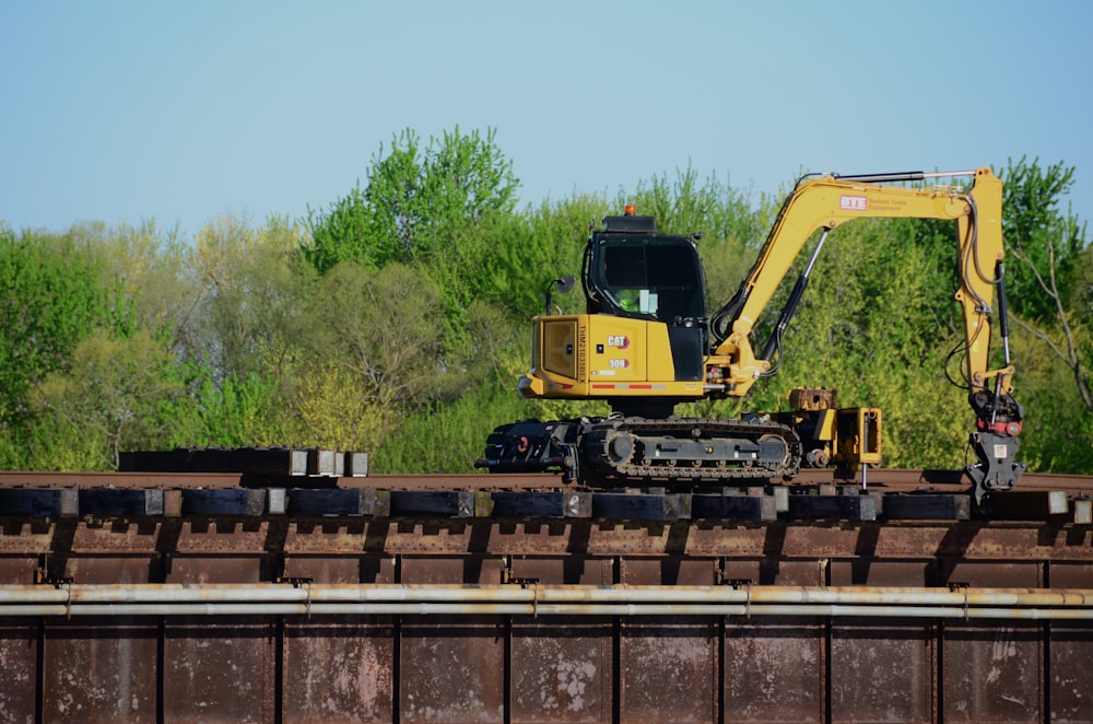 a yellow excavator sitting on top of a train track