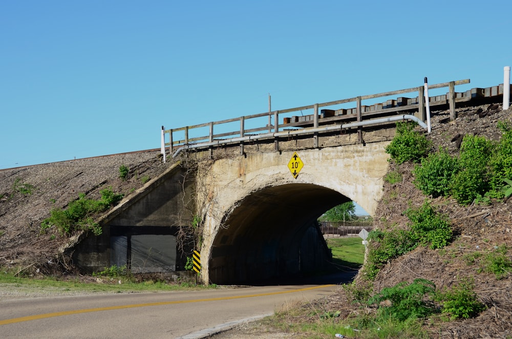 a bridge over a road with a yellow sign on it