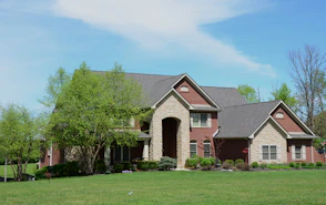 a large brick house with a green lawn in front of it