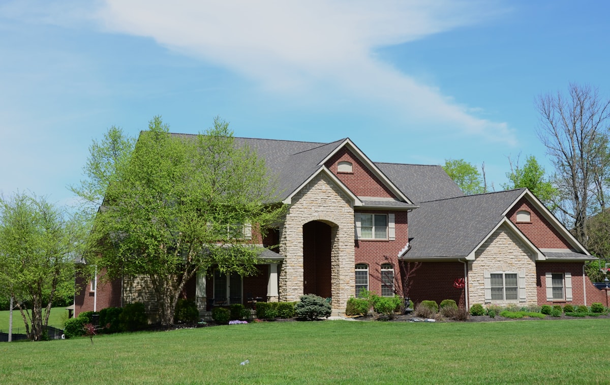 Large brick house with professionally landscaped green lawn in front