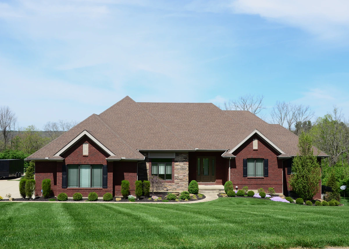 Brick ranch home with diagonal striped front lawn, mulched foundation beds, and curb-facing landscaping