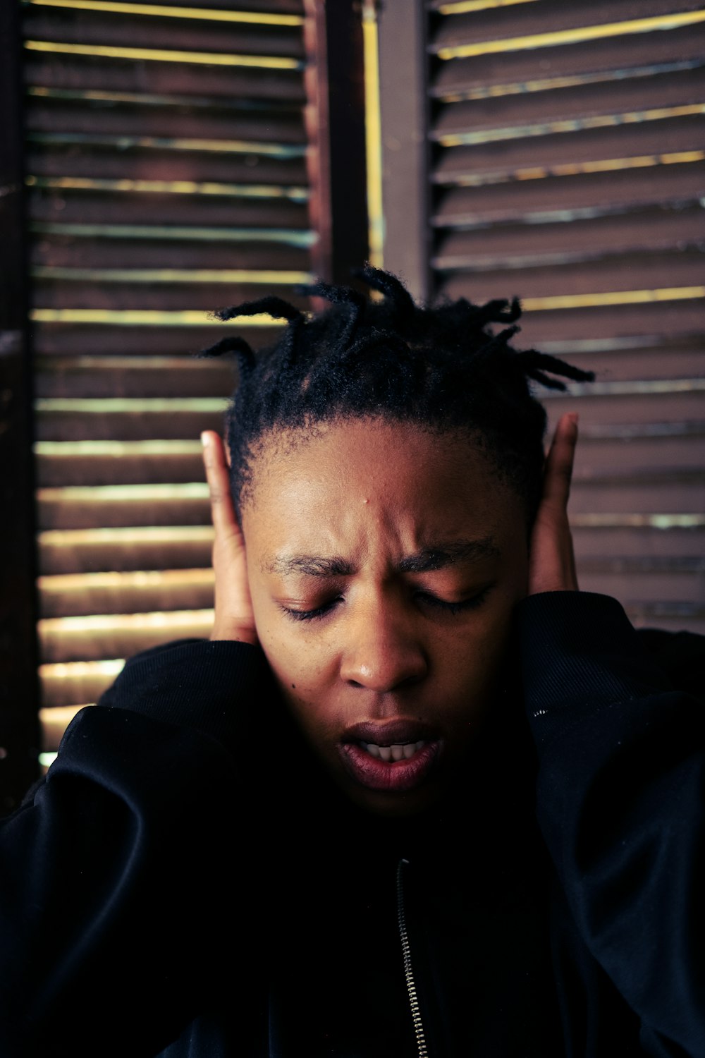 a woman with dreadlocks covering her ears