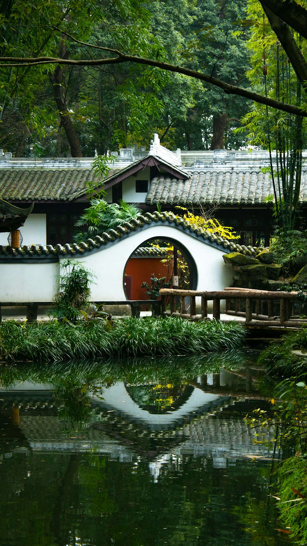 a pond in front of a white building with a red door