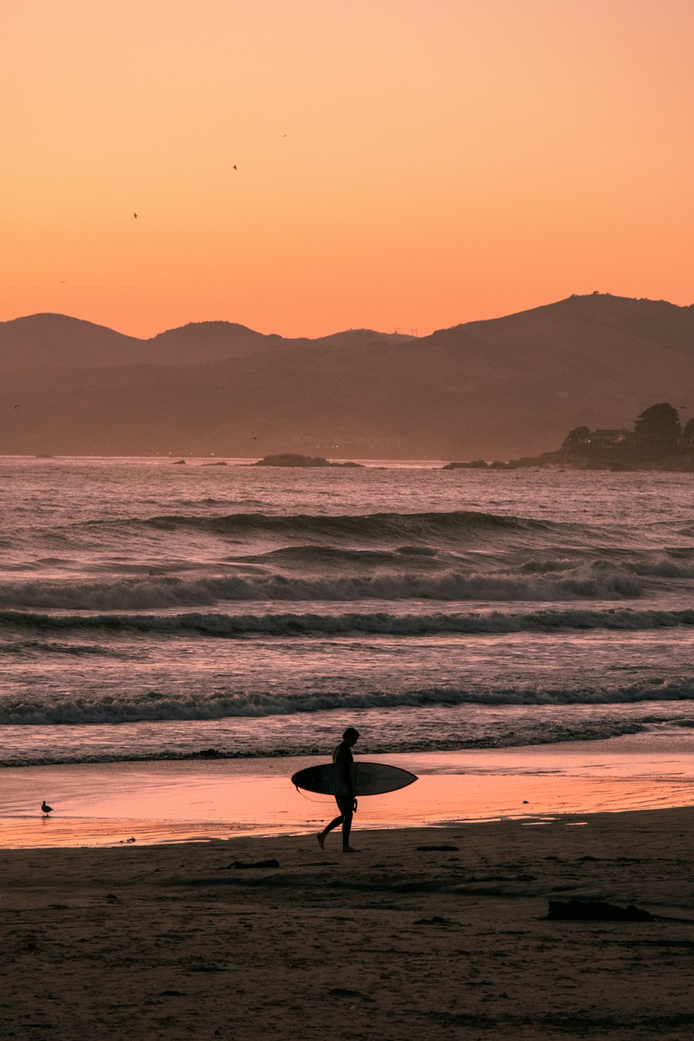 a person holding a surfboard on a beach