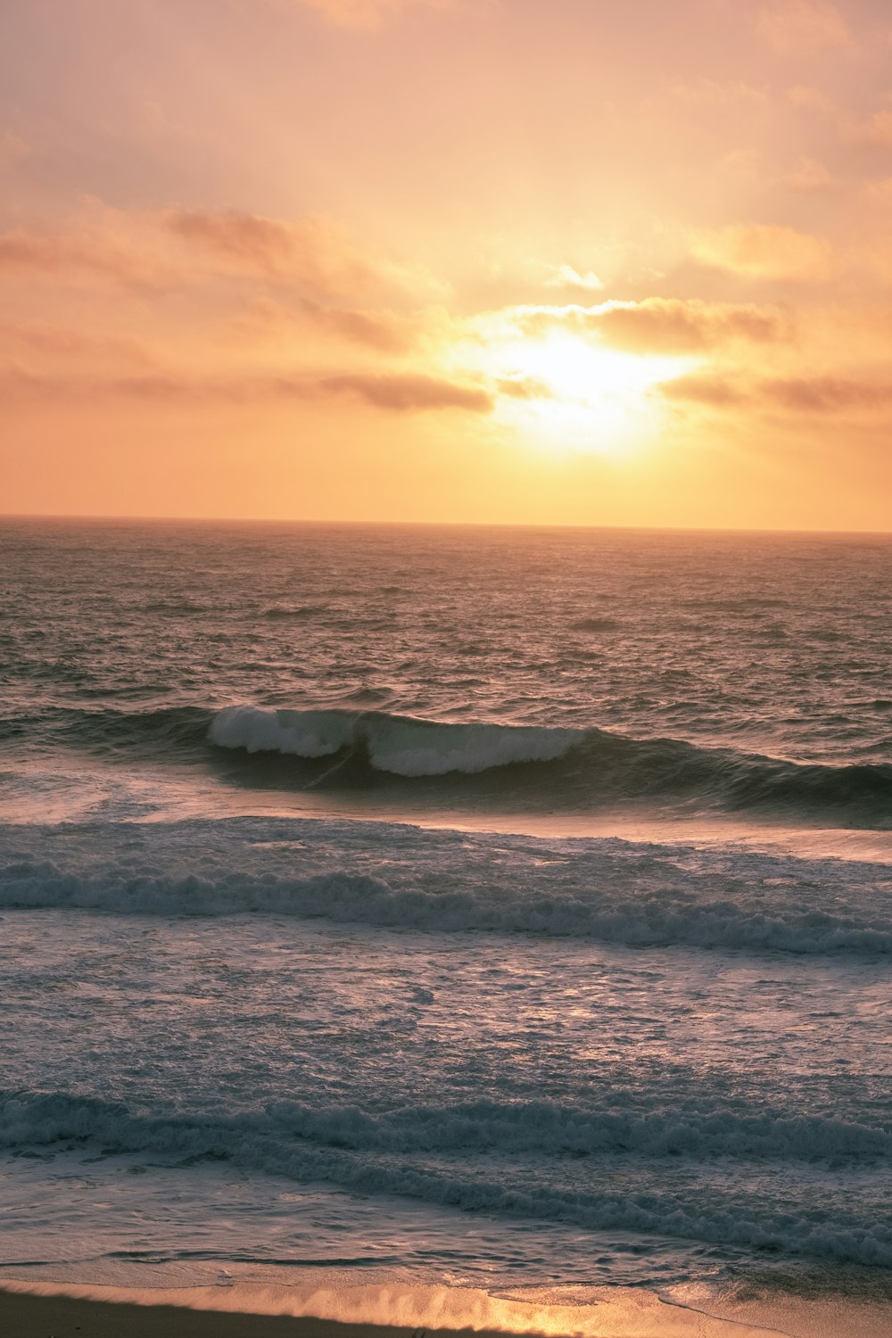 the sun is setting over the ocean waves