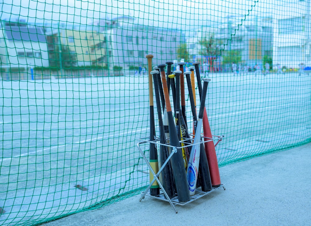 a rack of baseball bats on the side of a fence