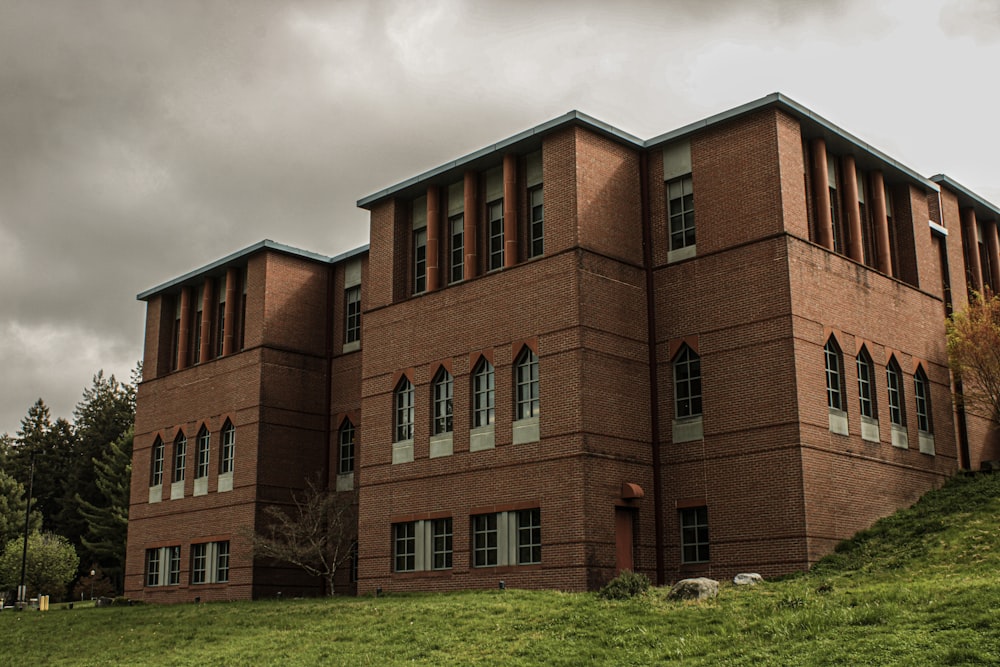 a red brick building on a hill under a cloudy sky