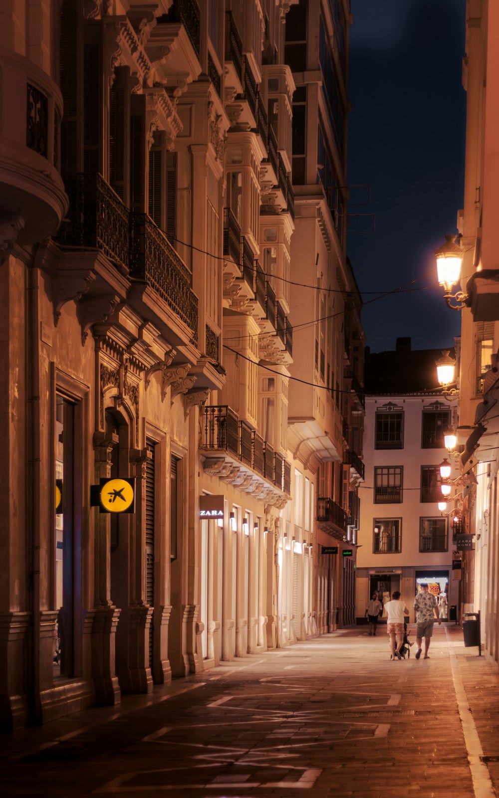 a couple of people walking down a street at night