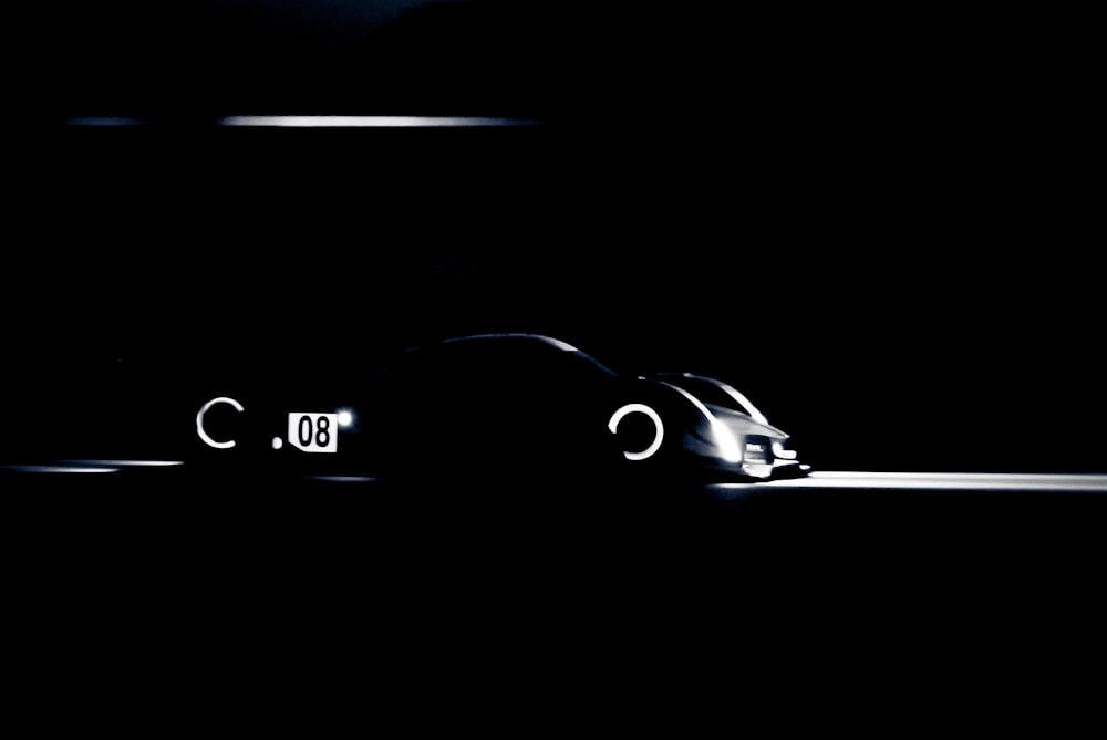 Une voiture est montrée dans l’obscurité avec ses phares allumés