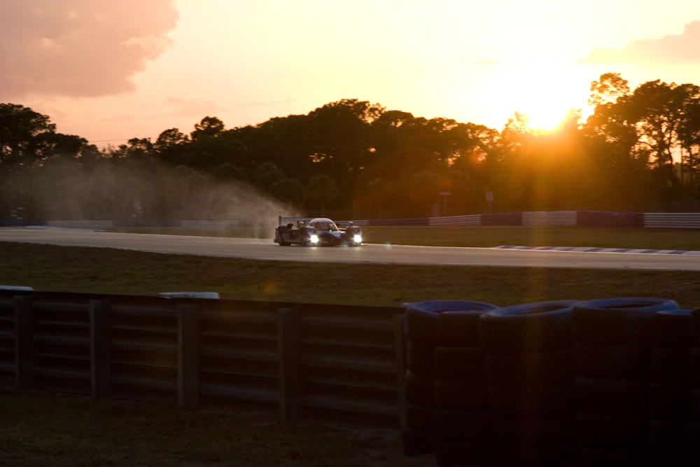a car driving down a race track at sunset