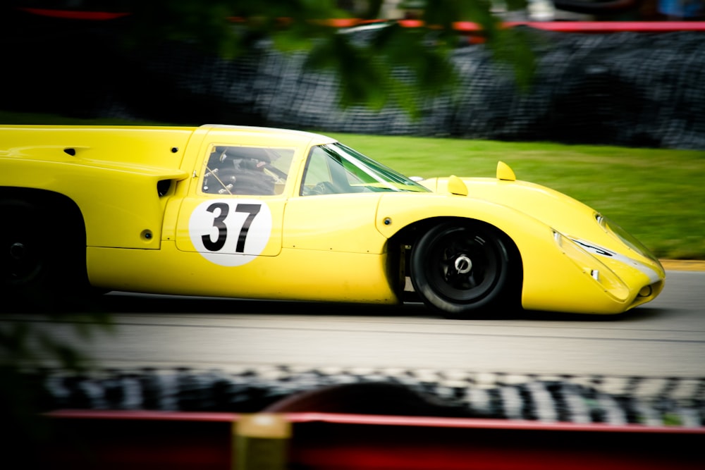 a yellow race car driving down a race track