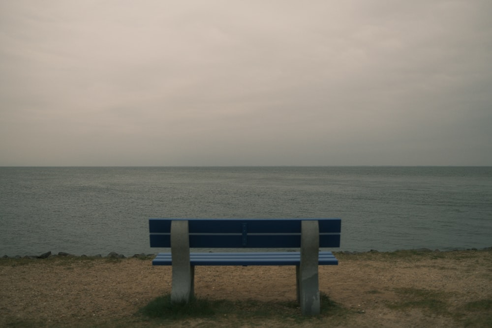 a blue bench sitting on top of a sandy beach