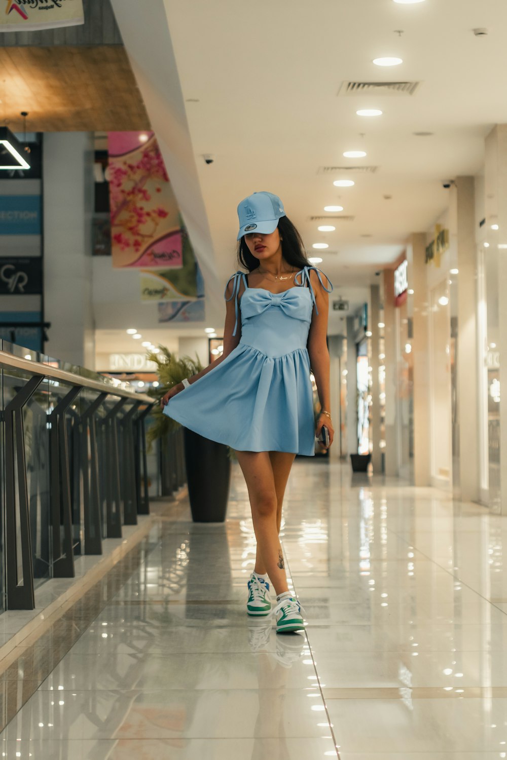 a woman in a blue dress and hat walking down a hallway