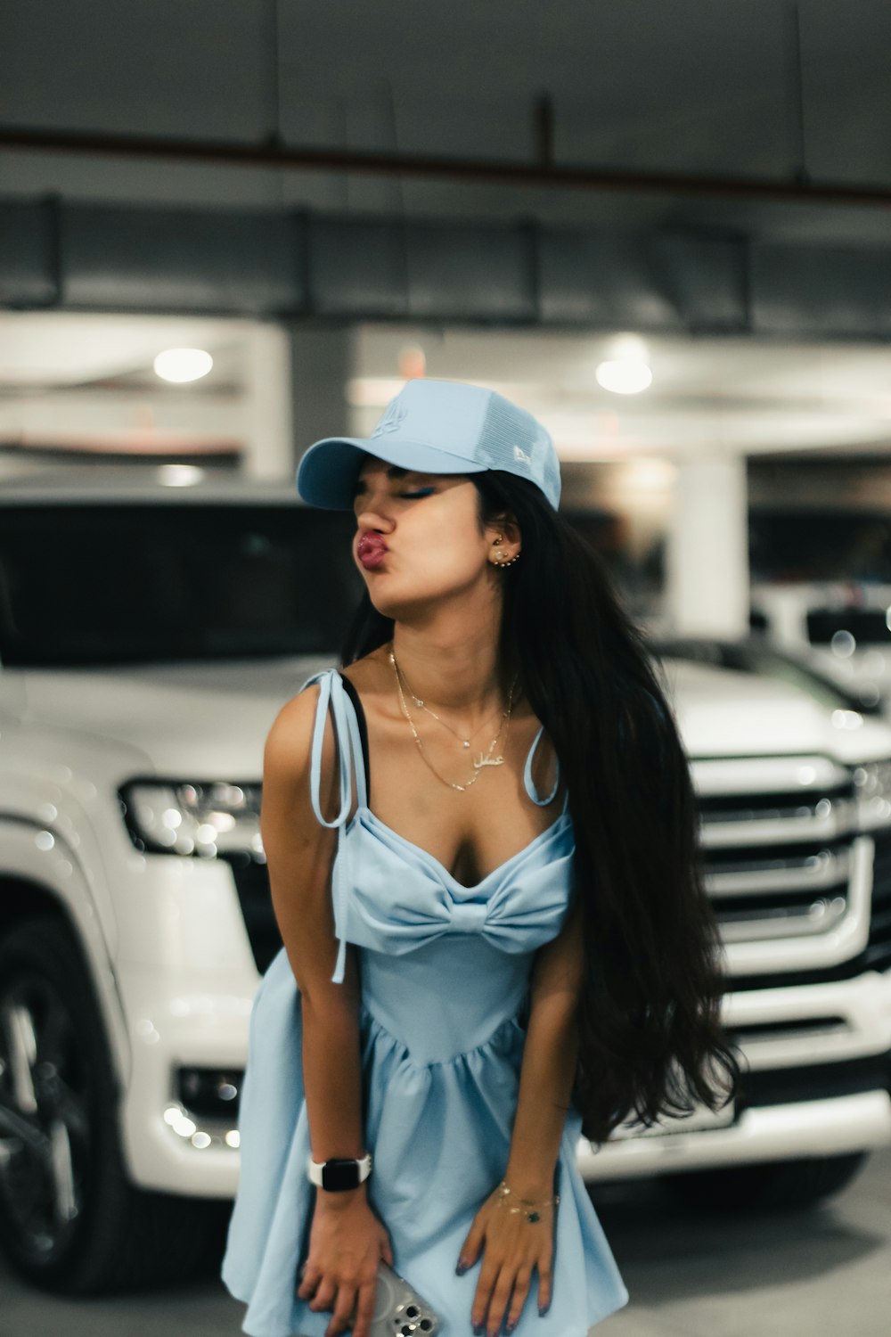 a woman in a blue dress and hat standing in front of a car