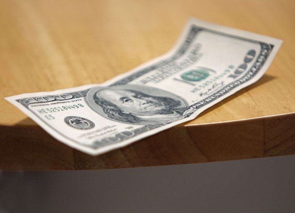 a one dollar bill sitting on top of a wooden table