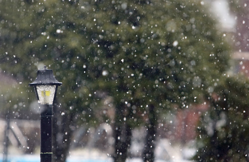 a street light sitting on the side of a road covered in snow