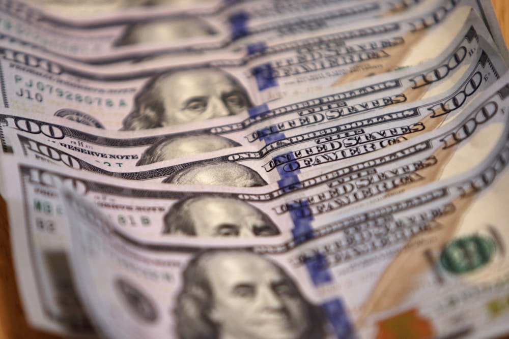 a stack of twenty dollar bills sitting on top of a wooden table