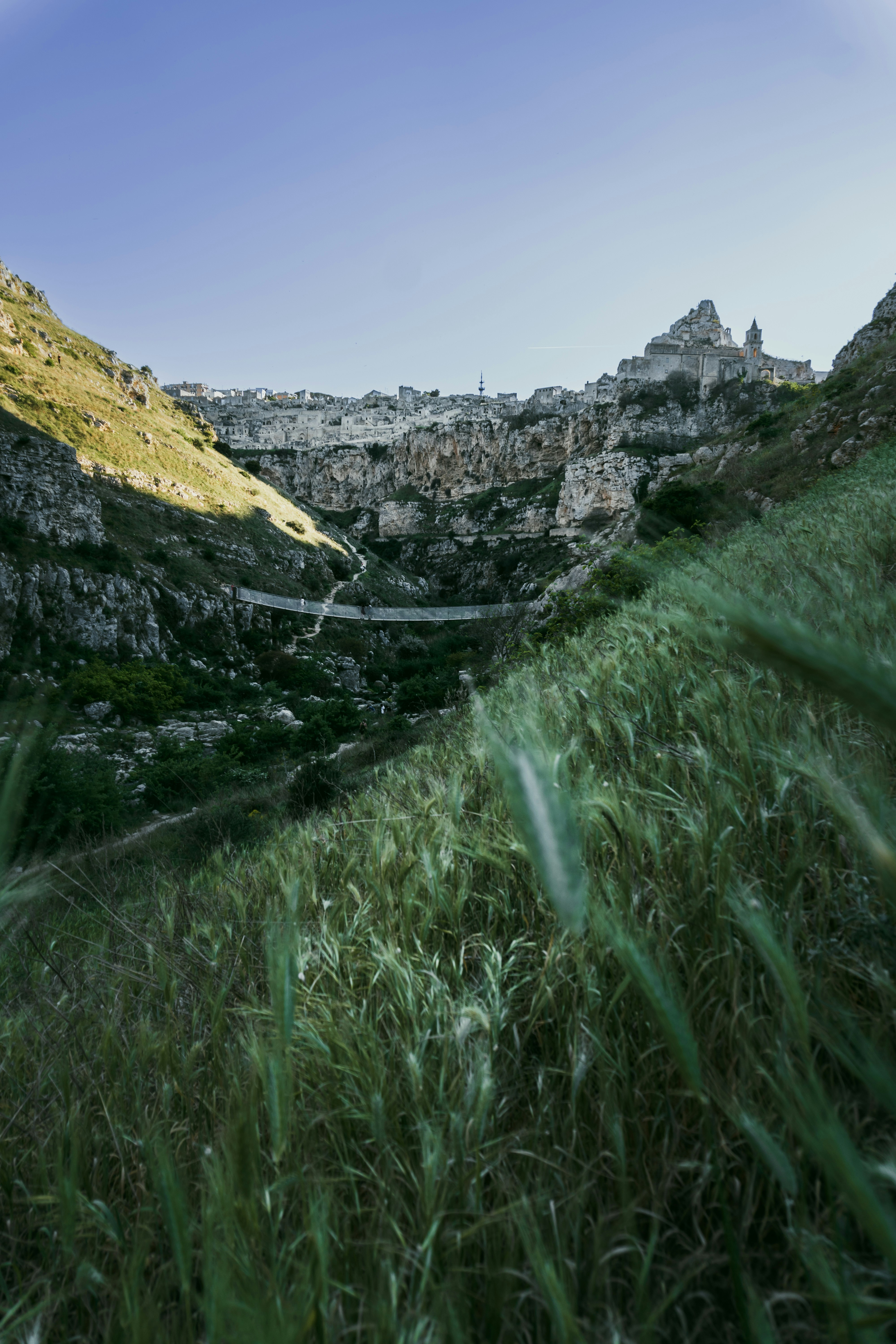 a grassy hill with a bridge in the distance