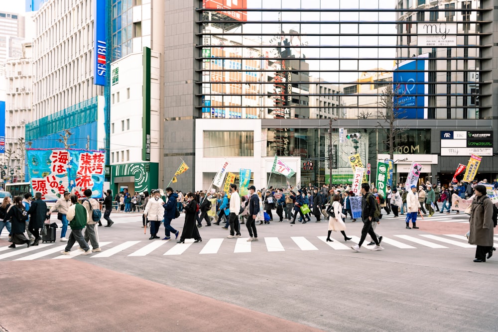 a crowd of people crossing a street in a city