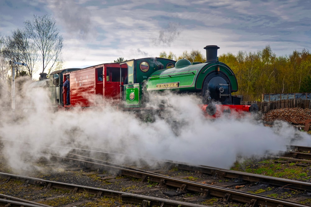 a green and red train traveling down train tracks