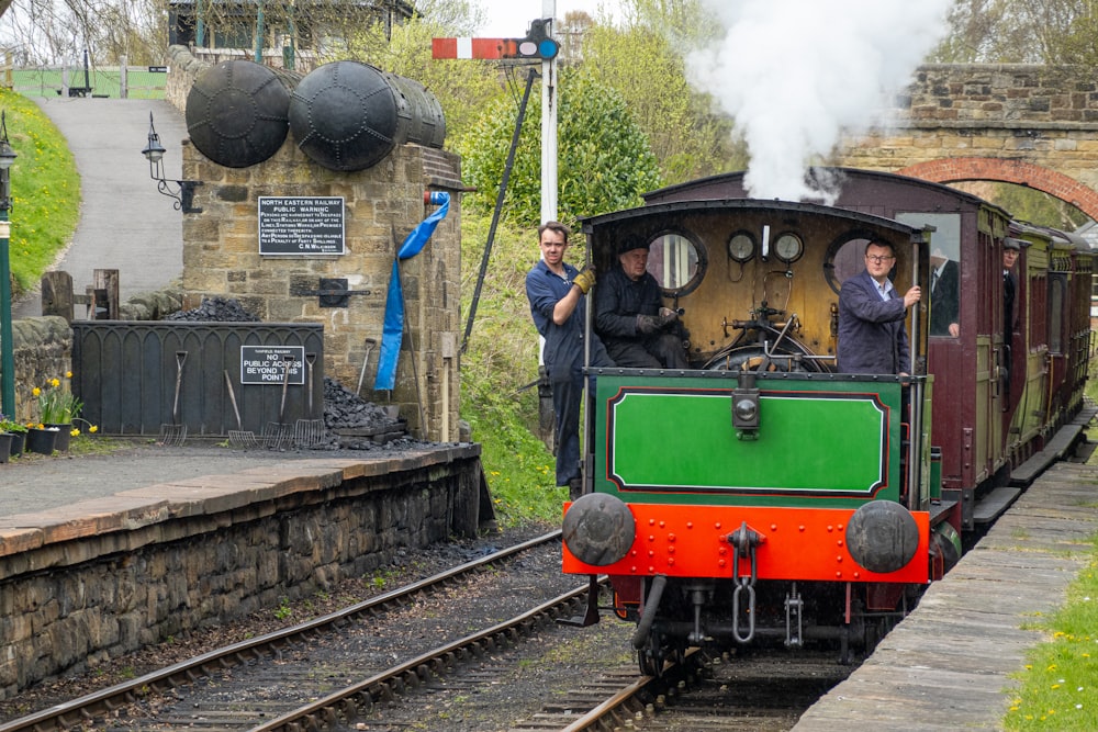 a green and red train traveling down train tracks