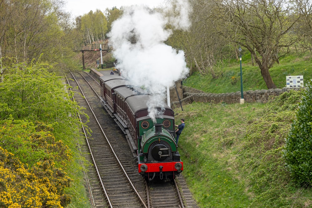 a steam train traveling down train tracks next to a forest