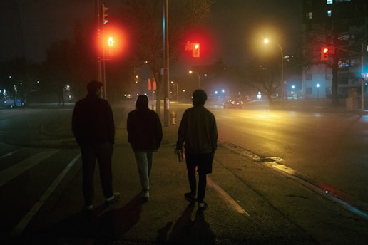 three people walking down a street at night