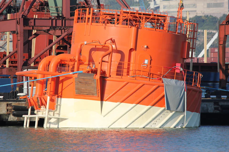 Orange single point mooring buoy with its piping and handrails, alongside a quay