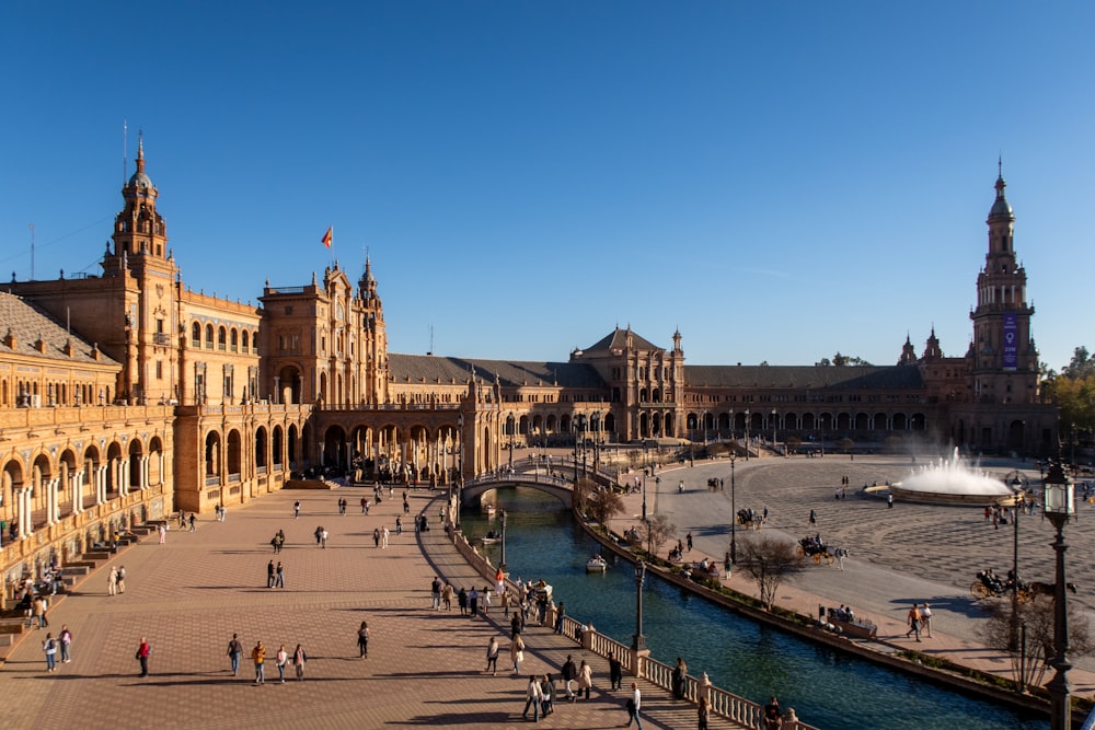 a group of people walking around a plaza next to a river