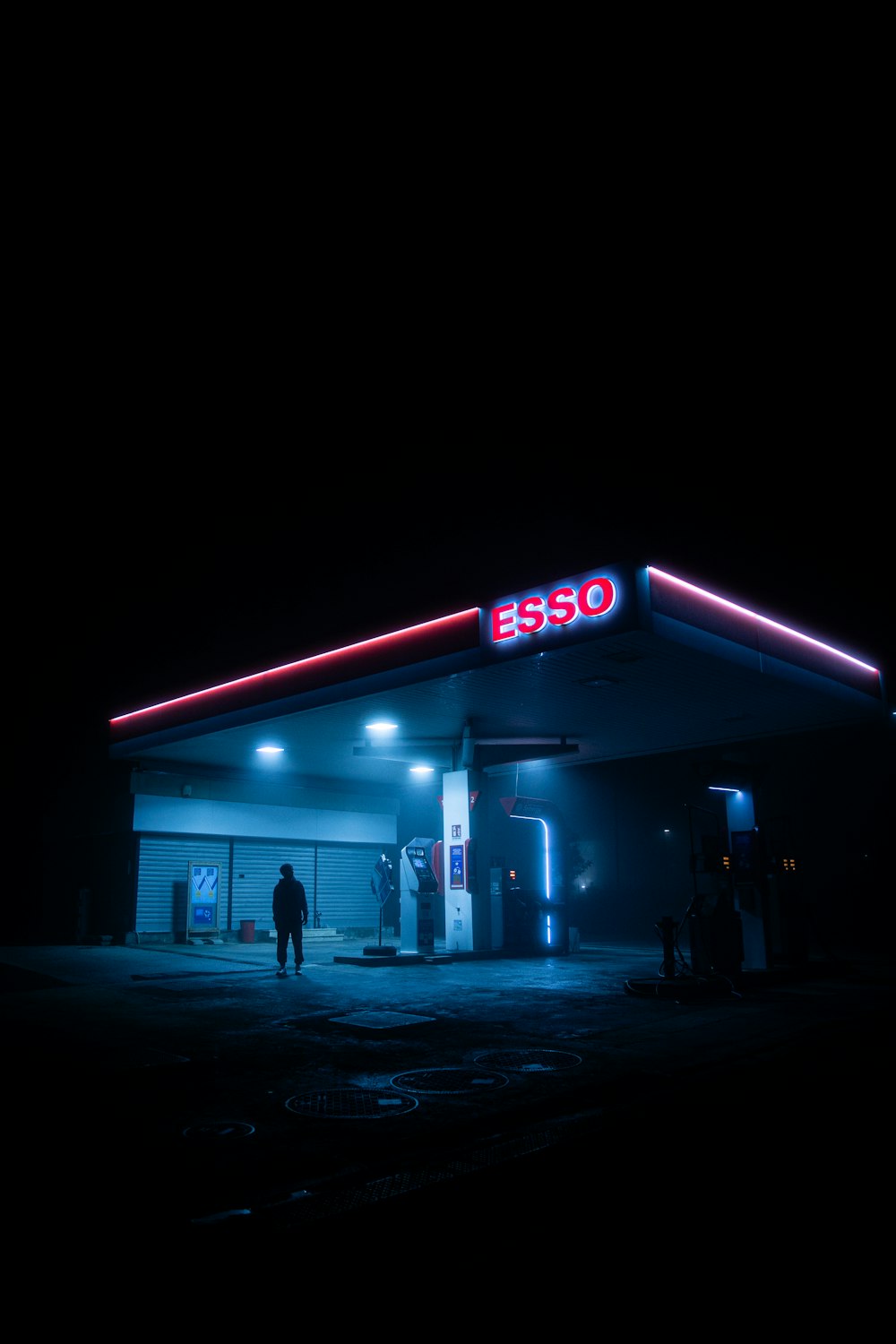 a gas station lit up at night with people standing outside